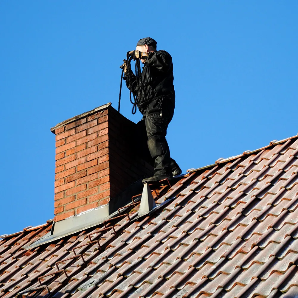 Technician inspecting a chimney on a tiled residential roof